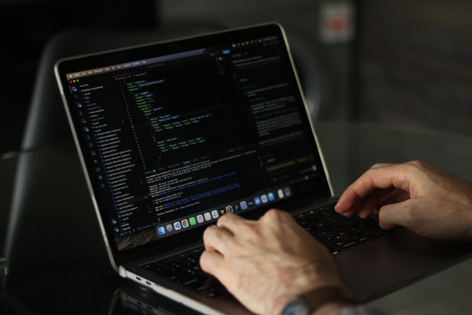 A computer screen displaying blurred lines of colorful programming code, including keywords, variables, and functions in shades of red, green, blue, yellow, and white, with a dark background. The code